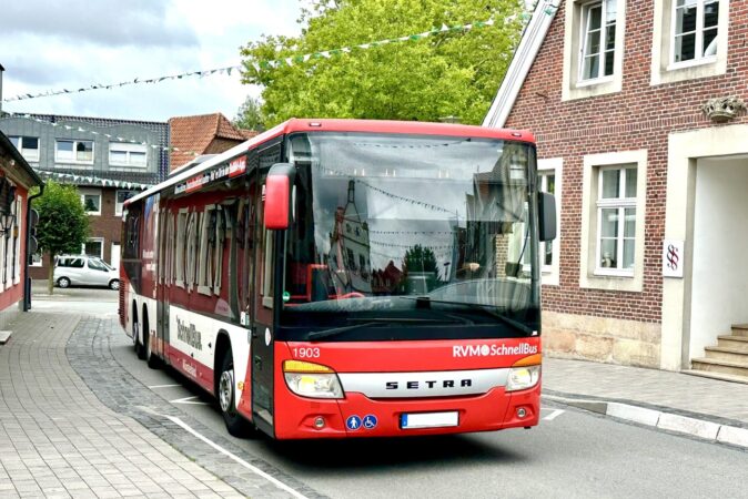 Ein roter Bus an einer Haltestelle.